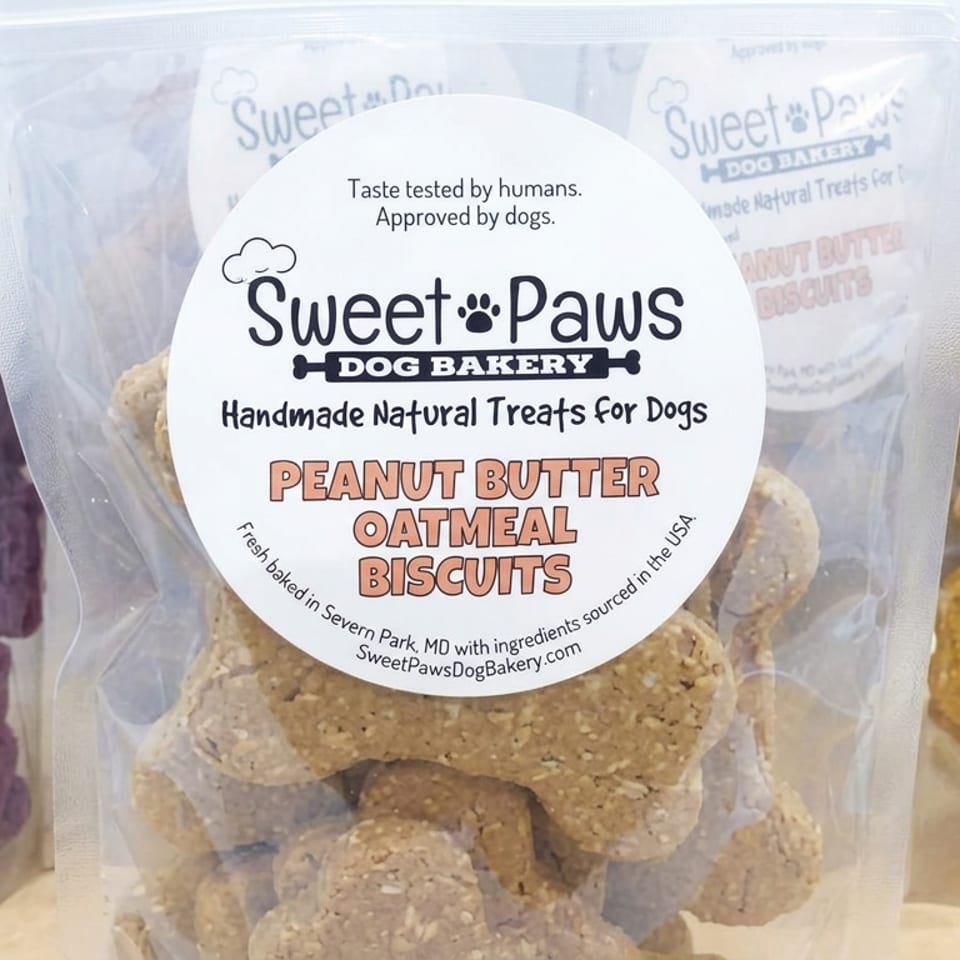 Packages of Sweet Paws Dog Bakery treats, including peanut butter oatmeal, blueberry, and hokey pokey biscuits.